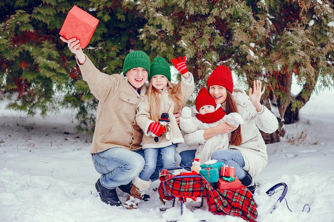 A family with wrapped gifts sits in the snow, showcasing festive holiday tours.