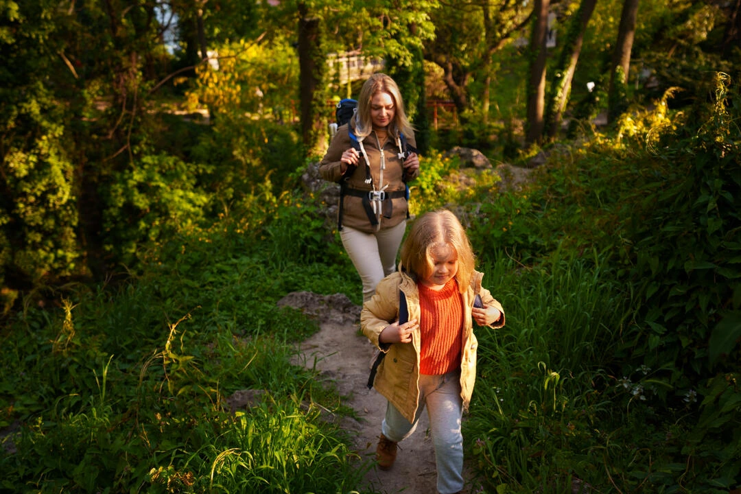 Child and adult walking on a forest path, showcasing serene nature exploration.